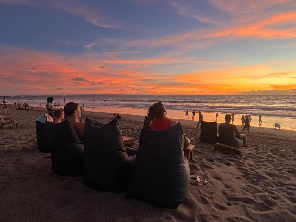 Travelers relaxing on beanbags at Canggu Beach while watching the sunset in Bali